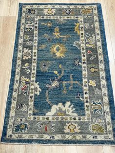 a blue rug with an ornate design on the middle and bottom, sitting on a wooden floor