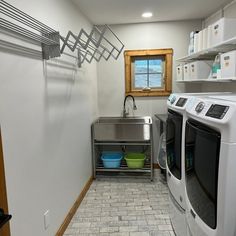 a washer and dryer in a small room with tile flooring on the walls