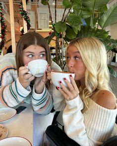 two women sitting at a table drinking coffee