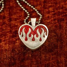 The sterling silver hearts on fire pendant features a chunky design and a stunning ruby red opal inlay (or your chosen inlay). Alternatively, you can opt for a transparent pendant without any inlay. It boasts a substantial 4 mm thickness and stands 26 mm tall. PLEASE READ: The production and delivery of your piece may take anywhere from 2-4 weeks as it is custom made by a real person. Grit Trade Co. is a curated collection of unique sterling silver jewelry inspired by American culture, music, an Unique Red Heart Shaped Jewelry, Red Heart-shaped Engraved Jewelry, Red Sterling Silver Heart Pendant Jewelry, Red Engraved Heart-shaped Jewelry, Red Polished Jewelry For Valentine's Day, Collectible Sterling Silver Jewelry For Valentine's Day, Unique Silver Jewelry For Valentine's Day, Heart Flame, Opal Heart Necklace