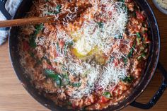 a pot filled with pasta and cheese on top of a wooden table next to a bowl of rice