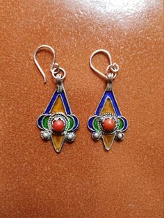 "The colorful earrings are made of enameled silver from Morocco.  The ear wires are sterling silver.  Total length is 13/4.\"  They are very light, about .04 ounces each.  The colors are yellow, green, and blue with a coral bead in the center." Enamel Dangle Single Earring, Green Enamel Single Earring, Single Green Enamel Earring, Single Enamel Drop Earring, Pierced Dangle Earrings In Enamel, Yellow Sterling Silver Single Earring, Nickel-free Enamel Drop Earrings, Artisan Enamel Jewelry With Ear Wire, Multicolor Enamel Teardrop Jewelry