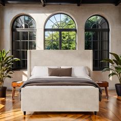 a large bed sitting inside of a bedroom next to two planters on either side of the bed