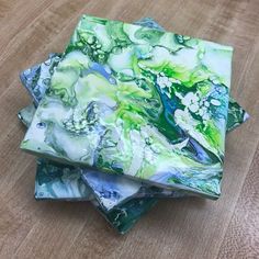 four pieces of glass sitting on top of a wooden table with green and blue designs