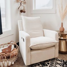 a white chair sitting next to a window in a room with a rug on the floor