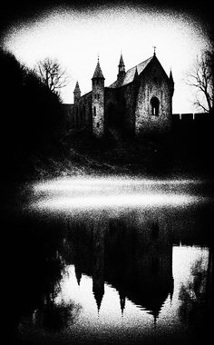 a black and white photo of an old church on a hill with water in the foreground