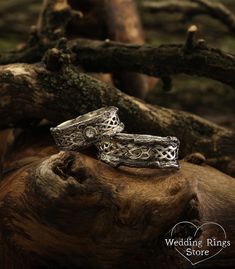 two wedding rings sitting on top of a tree branch in front of a heart shaped log