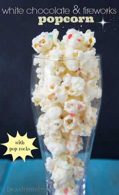 white chocolate and fireworks popcorn with pop rocks in a clear glass on a blue table