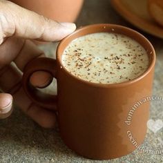 a person holding a coffee cup in their left hand and pointing to the mug on the right