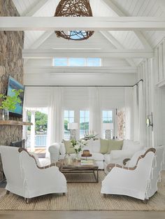 a living room filled with white furniture and windows