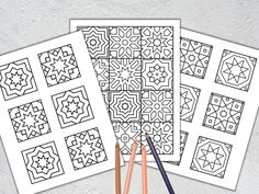 three coloring pages with pencils on top of them and one has an intricate design