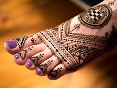 a woman's foot with hennap on it and purple nail polishes