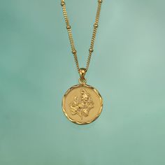 a gold necklace with an image of a man on it's face is shown against a blue background