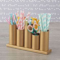 a set of four pencils, scissors and other office supplies in a gold cup