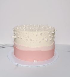 a white and pink cake with pearls on top