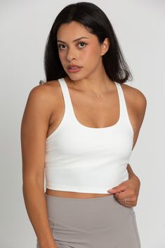 Our White Racerback Crop Tank features a slight cropped fit and racerback style that is the perfect go-to athletic top. It is complete with sweat-wicking material and a double layer, built-in-removable padded bra. 75% Nylon, 25% Spandex Built in / Removable Padding Model Details: Modeled in size: Small, Small Model Waist: 26, 30 Model Bust: 33, 34 Model Height: 5'3, 5'6 Sporty Scoop Neck Tank Top With Built-in Padding, Sporty Stretch Tank Top With Built-in Padding, Racerback Tops With Built-in Bra For Light Sports, Stretch Tank Sports Bra With Built-in Padding, Sporty Racerback Tank Top With Built-in Padding, Compressive Crop Top With Built-in Padding For Workout, Casual Sports Crop Top With Built-in Bra, Racerback Tops With Built-in Padding And Medium Support, Scoop Neck Tank Top With Built-in Padding For Gym