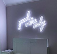 there is a neon sign that says good vibes only on the wall above a bed