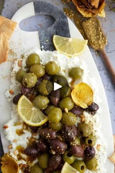 an image of food on a plate with lemons and olives