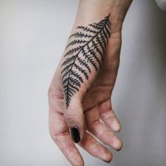 a hand with a fern tattoo on it's left arm and the other hand is holding