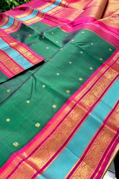 Introducing this magnificent handwoven korvai kanjivaram silk saree, adorned with buttis in rich emerald green body and deep pink contrast beautifully in the border and pallu, accentuated by a rama blue woven band and traditional gold zari motifs. Experience a perfect blend of traditional Indian artistry and modern elegance. Approximate Length 6.5 mtrs (inclusive of blouse length) Approximate Height - 48 - 52" Approximate weight - 1.7 lbs Saree comes with fall, picot and tassels done when applicable. Blouse piece is cut. Kindly Note : The colors you see on your device may vary due to the color reproduction, brightness and resolution of individual devices. If you'd like more clarity before your purchase, please contact our support team. Green Cotton Silk Traditional Wear With Drape, Green Cotton Silk Traditional Wear For Festivals, Green Handloom Cotton Silk Saree, Green Cotton Silk Handloom Saree, Traditional Green Cotton Silk Saree, Green Cotton Silk Saree With Zari Weaving, Green Cotton Silk Saree For Festivals, Green Tussar Silk Saree With Border, Festive Green Saree With Border