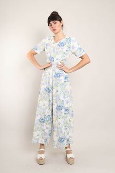 FEATURES - 1990s jumpsuit - White, periwinkle, blue, green colors - Muted floral print - Short sleeves - V-neckline - Slightly fitted waist - Flowing wide leg pants - Zips up the back CONDITION Good vintage condition: super faint discoloration along the front of the neckline; very edge of the bottom hem of the pants has some light dirt-like markings. MEASUREMENTS & FIT suggested letter size: S/M shoulder: 14.5" bust (underarm): 35"-36" waist: 31" hip: 44" length: 58" inseam: 26.5" shoulder to crotch: 31" sleeve: 10" color: white, periwinkle, blue, green material: feels like rayon, zipper label: no label pinned on model? no Note on fit: Adrianne is 5'10 33-25-36 with a modern dress size 2-4, letter size XS/S and a size 26 in jeans. All items are measured while the garment is laying flat. Th Casual Floral Print Maxi Jumpsuits And Rompers, Floral Print Jumpsuits For Garden Party In Spring, Casual Fitted Jumpsuits For Garden Party, Floral Print Jumpsuit For Spring Garden Party, Floral Print Jumpsuits And Rompers For Garden Party, Casual Fitted Jumpsuits And Rompers For Garden Party, Fitted Floral Print Wide Leg Jumpsuits And Rompers, Fitted Floral Print Jumpsuits And Rompers With Wide Leg, Fitted Floral Print Jumpsuits For Garden Party