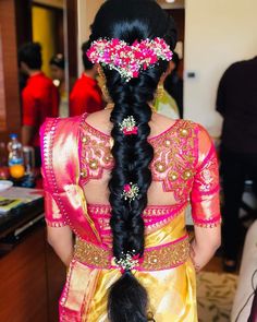 the back of a woman's head with braids and flowers in her hair