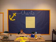 a child sitting at a desk in front of a bulletin board with an anchor on it