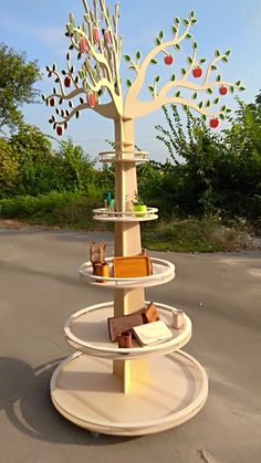 there is a tree made out of books on the ground with apple trees in it