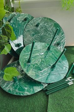 green plates and forks are sitting on the floor next to a potted leafy plant