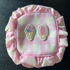 pink and white checkered fabric with ice cream pincuss on the front, sitting on a black surface