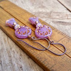 These beautiful purple earrings are sure to brighten anyone's day! These Czech glass bead compliment one another perfectly. The top bead is a 13mm purple sun wheel bead, with a bronze Picasso wash, filling in a subtle design. This is separated from the tulip bead by a 3x5 opal orange bead and a copper bead cap.The purple tulip bead has a repeat of the bronze wash on the edges of the bead, accenting the tulip shape. These earrings are also available with antique brass. Happy to put a titanium ear Sun Wheel, Purple Tulips, Earrings Purple, Purple Earrings, Lake Forest, Pretty Earrings, Delicate Earrings, Etsy Earrings Dangle, Purple Flower