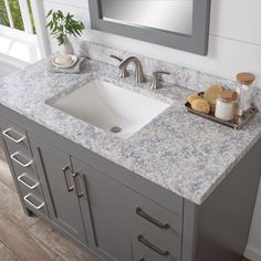 a bathroom sink sitting under a mirror on top of a counter next to a window