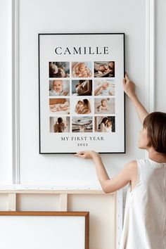 a woman standing in front of a white wall holding up a poster with pictures on it