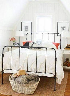 a bedroom with white walls and wood flooring has a black iron bed frame in the corner