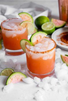 two glasses filled with watermelon margaritas on top of ice and lime slices