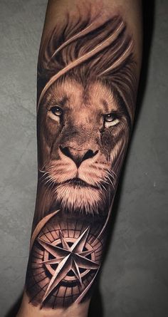 a man's arm with a lion and compass tattoo on it