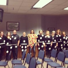 a group of people that are standing in front of a row of chairs with ribbons