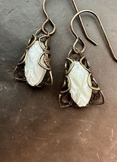 "These mother of pearl carved gorgeous stones have been UPCYCLED into earrings!!   Antique brass filigrees bring these beautiful deco stones back into circulation. The stones were uncovered from old warehouse jewelers stock. MINT condition and never designed with. The filigrees are Miriam Haskell vintage old stock findings. What a pairing!  1 1/4\" in length.  Stone size:  3/4\"  If you buy more than 5 items in the store, shipping is FREE." White Carved Earrings For Gift, Collectible Art Nouveau Carved Jewelry, Ornate Handmade White Jewelry, White Ornate Handmade Jewelry, White Handmade Ornate Jewelry, Ornate White Handmade Jewelry, Ornate White Carved Jewelry, White Art Nouveau Jewelry For Anniversary, White Art Nouveau Jewelry For Formal Occasions