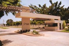 an empty parking lot in front of a large white building with trees on the other side