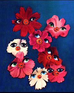 a vase filled with lots of red and white flowers next to blue eyes on top of a table