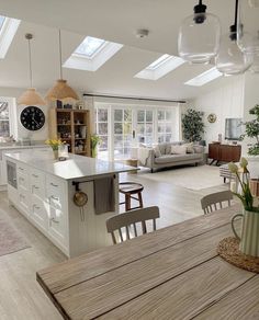 a large open concept kitchen and living room with skylights on the ceiling, dining table in foreground