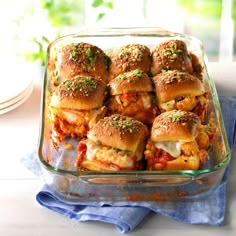 a glass casserole dish filled with sliders covered in marinara sauce and cheese