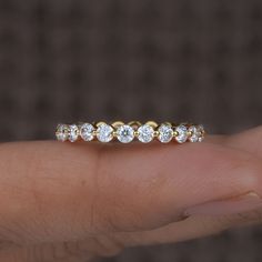 a woman's hand holding a gold and white diamond ring with five diamonds on it