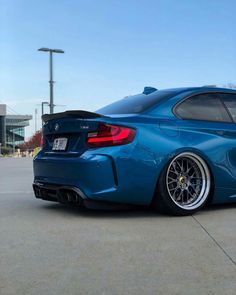 the rear end of a blue car parked in a parking lot