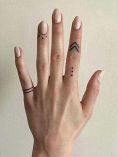 a woman's hand with two small tattoos on her left thumb and one finger