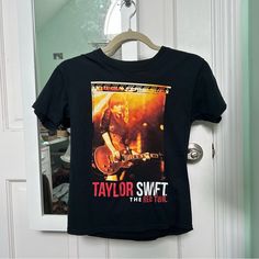 a black taylor swift t - shirt hanging on a door