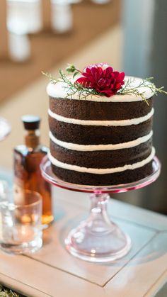 a chocolate cake with white frosting and red flowers on top is sitting on a table