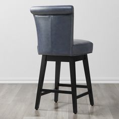 a black leather bar stool in front of a white wall and hardwood flooring with an upholstered backrest