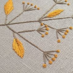 some yellow flowers and leaves on a white surface with thread work in the middle that has been stitched together