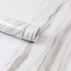 a roll of white tape sitting on top of a marble wallpaper covered in grey and white stripes